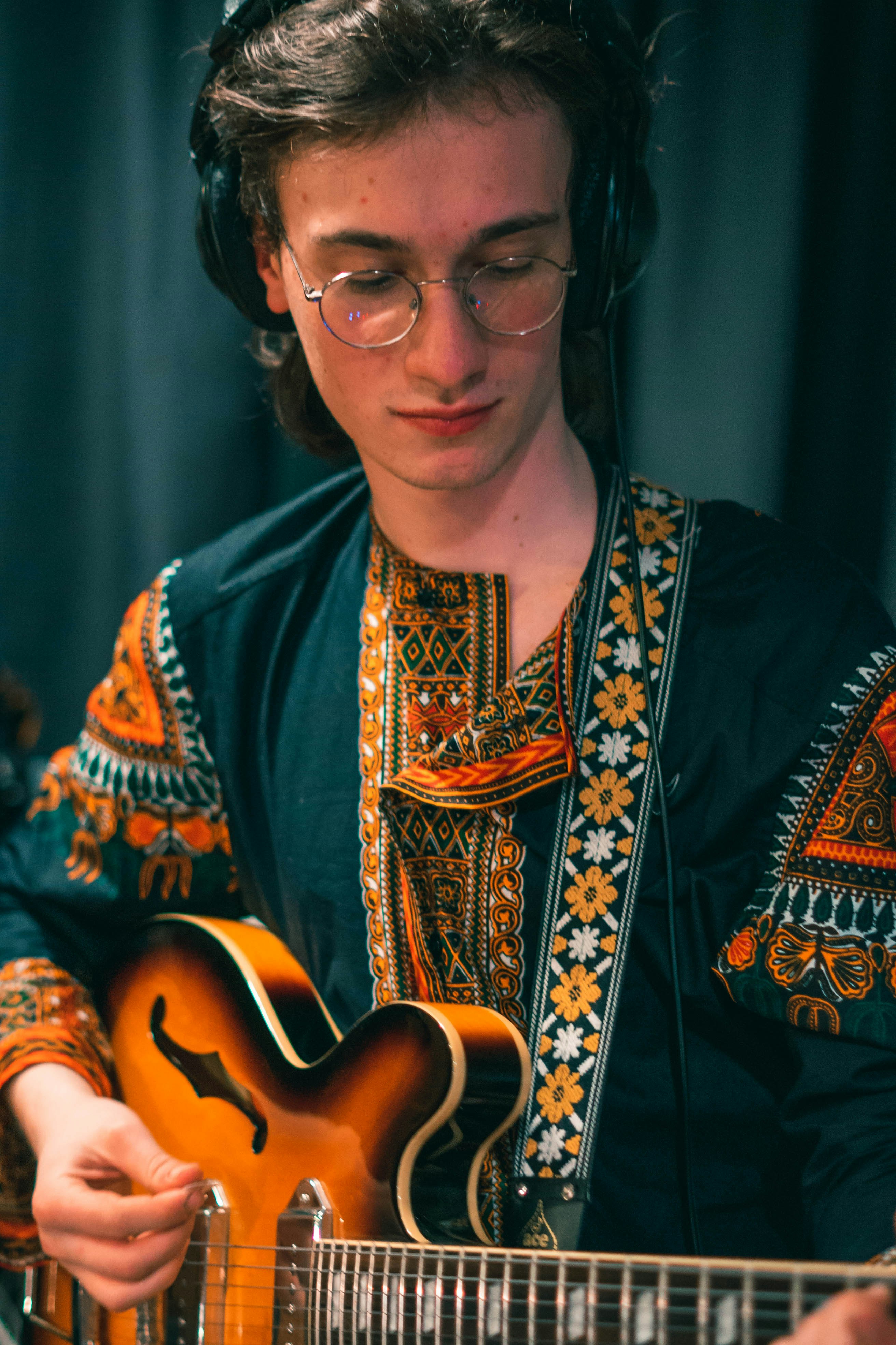 woman in blue and brown floral dress holding brown acoustic guitar